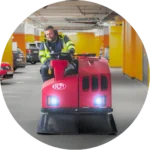 Sopmaskinist kör en röd städmaskin i parkeringsgarage – PL Utemiljö utför professionell garagestädning.