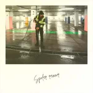 En PL arbetare i reflexkläder spolar rännor med högtryck i ett tomt parkeringsgarage.